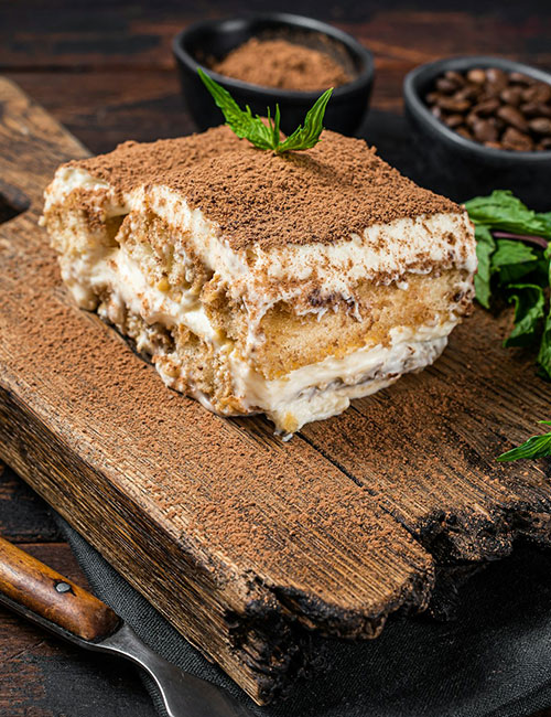 italian-dessert-tiramisu-cake-with-cocoa-and-mint-on-a-wooden-board-dark.jpg